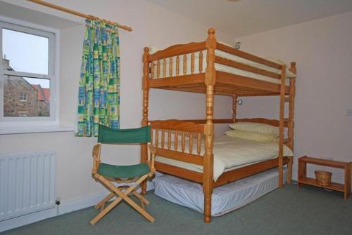 a bedroom with a bunk bed and a chair at Snook Point Cottage in Newton-by-the-Sea