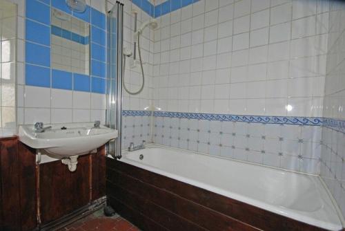 y baño con lavamanos, bañera y lavamanos. en Roughley Cottage en Newcastleton