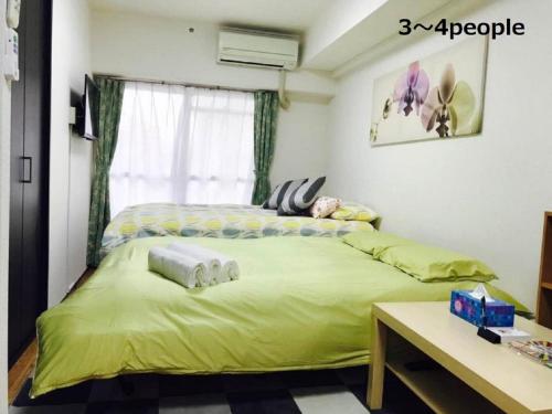 a bedroom with a large bed with yellow sheets at Sun Heights Ikebukuro in Tokyo