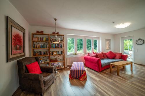 ein Wohnzimmer mit einem roten Sofa und einem Stuhl in der Unterkunft Ferienbungalow Sonnenwald Bayerischer Wald in Schöfweg