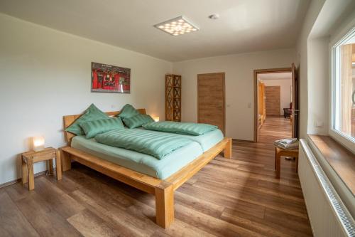 ein Schlafzimmer mit einem großen Bett mit grünen Kissen in der Unterkunft Ferienbungalow Sonnenwald Bayerischer Wald in Schöfweg