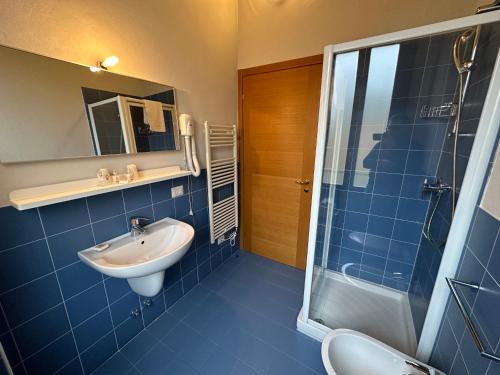 a blue tiled bathroom with a sink and a shower at Domus San Bernardino in Verona