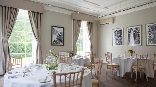 a room with white tables and chairs and windows at Eastwood Hall in Eastwood