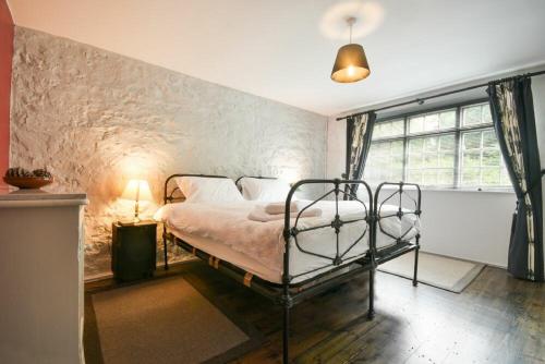 a bedroom with a bed in a room with a stone wall at Stonecrop Cottage in Alwinton