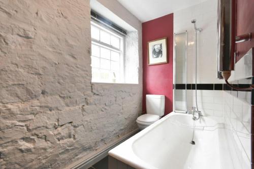 a bathroom with a white tub and a toilet at Stonecrop Cottage in Alwinton