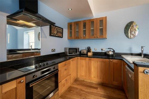 a kitchen with wooden cabinets and a stove top oven at Pilots Rest in Alnmouth