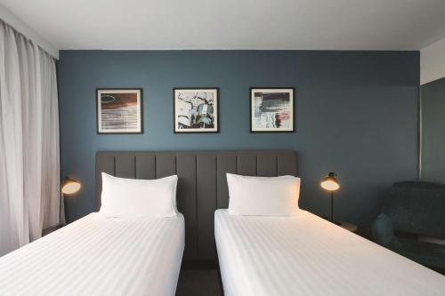 two beds in a room with blue walls at Travelodge Hotel Hobart in Hobart