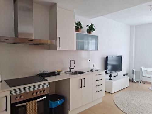 a kitchen with white cabinets and a sink and a tv at Precioso loft al lado Parc Vallparadís by Lofties in Terrassa