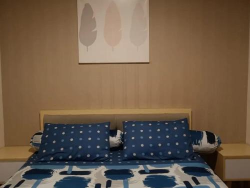 Schlafzimmer mit einem Bett mit blauen und weißen Kissen in der Unterkunft Maxxy room grand Kamala lagoon in Pulosirih