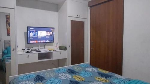 Schlafzimmer mit einem Bett, einem TV und einem Schreibtisch in der Unterkunft Maxxy room grand Kamala lagoon in Pulosirih