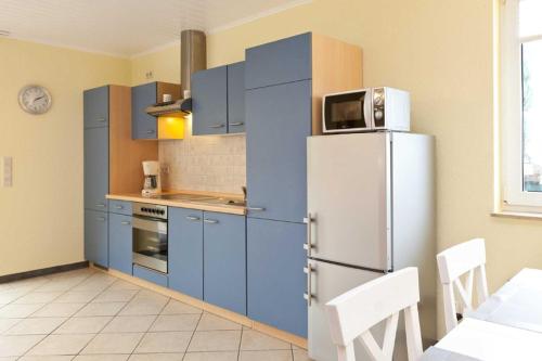 eine Küche mit blauen Schränken und einem Kühlschrank in der Unterkunft FH Wendorff in Klink