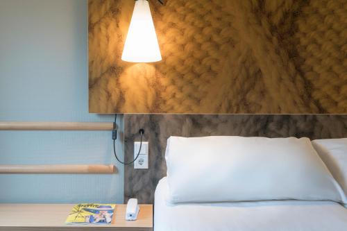 a bedroom with a bed and a light on the wall at Ibis Irun in Irún