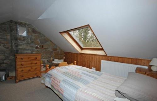 a attic bedroom with a bed and a window at The Old School House in Alwinton
