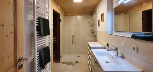 a bathroom with a sink and a shower and a mirror at Ferienhaus Happyplace in Illach