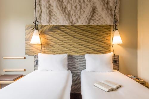 two beds in a room with two lamps at Ibis Irun in Irún