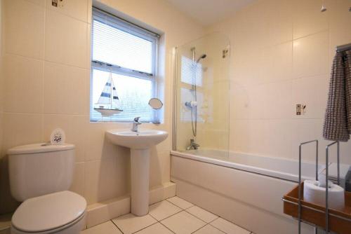 a bathroom with a toilet and a sink and a window at Beachcomber Apartment in Bamburgh