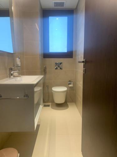 a bathroom with a toilet and a sink and a window at Townhouse Paolo in Salalah
