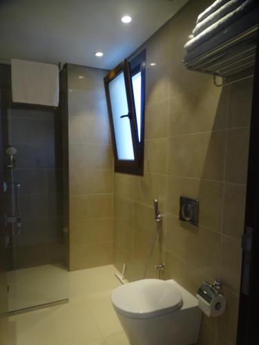 a bathroom with a toilet and a window at Townhouse Paolo in Salalah