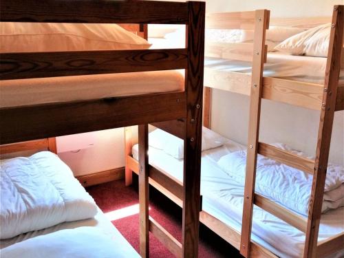 a room with three bunk beds with white sheets at Appartement Morillon 1100, 3 pièces, 6 personnes - FR-1-412-55 in Morillon