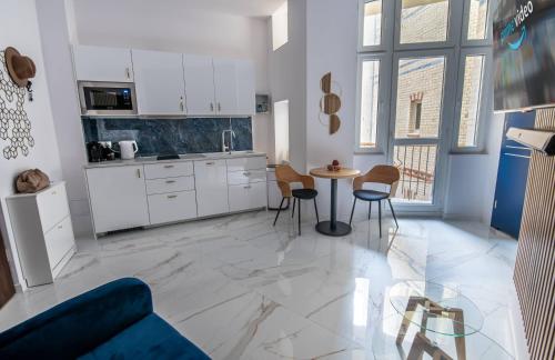 a kitchen with white cabinets and a table and chairs at Apartamenty Yeti & Wilka w Centrum Chorzowa - Yeti in Chorzów