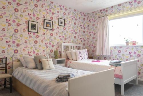 two beds in a room with pink floral wallpaper at Our Story Cottage in Long Houghton