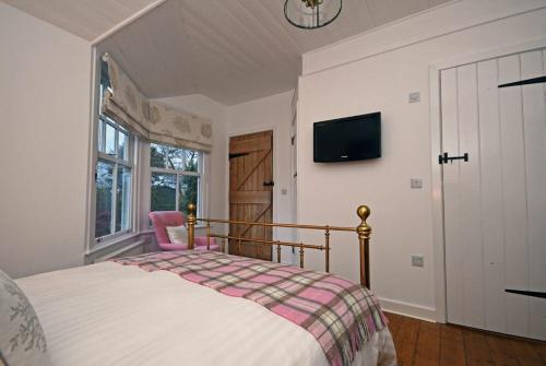 a bedroom with a bed and a tv on the wall at Periwinkle in Bamburgh