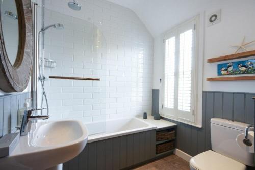 a bathroom with a sink and a tub and a mirror at Periwinkle in Bamburgh