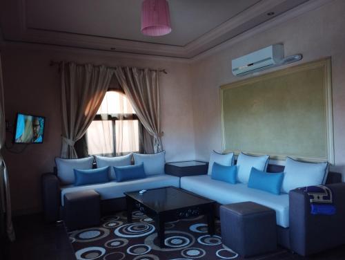 a living room with a couch with blue pillows at ApartHotel Nzaha in Tahannout