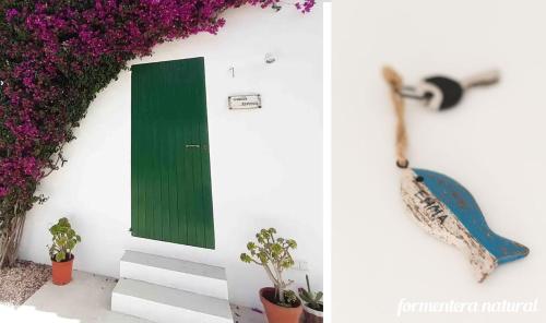 zielone drzwi na białej ścianie z fioletowymi kwiatami w obiekcie Casas Emma y Sofía - Porto Sale - Formentera Natural w mieście Sant Francesc Xavier