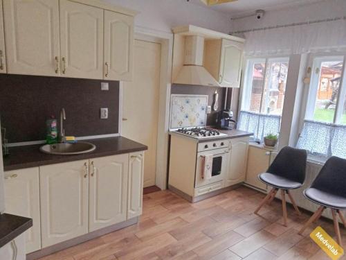 a kitchen with white cabinets and a sink and a stove at Pensiunea Laba Ursului - Medveláb Vendégház in Sovata