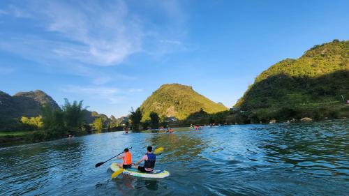 two people on kayaks on a river with mountains at Nasan Green Farm in Cao Bằng