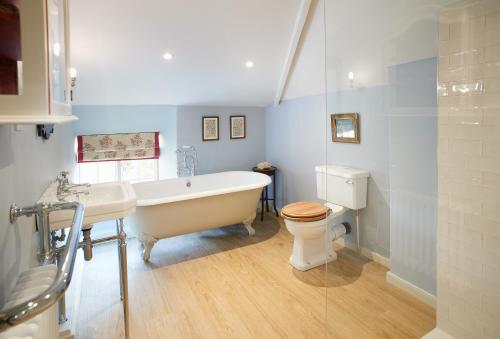 a bathroom with a tub and a toilet and a sink at Chanting Hill Farmhouse at Castle Howard in Welburn