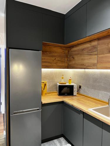 a kitchen with black cabinets and a stainless steel refrigerator at Emma Park Lake in Tuzla