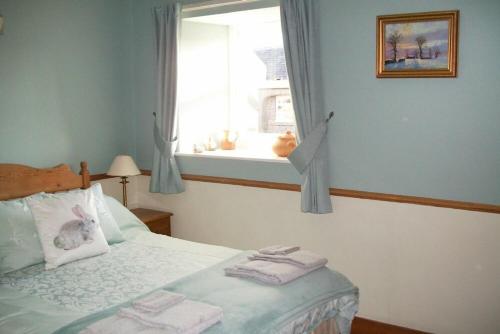 1 dormitorio con 1 cama y ventana con toallas en Swallow Cottage nr Powburn en Ingram