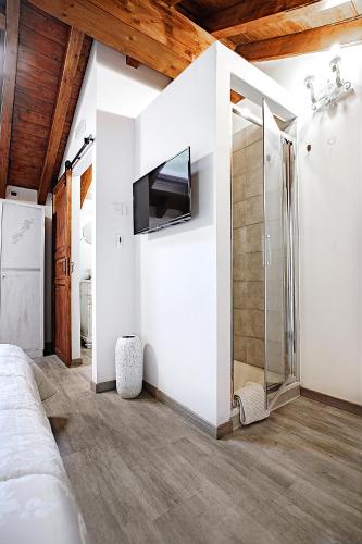 a bedroom with white walls and a tv on a wall at Il Castagno in Castiglione dei Pepoli