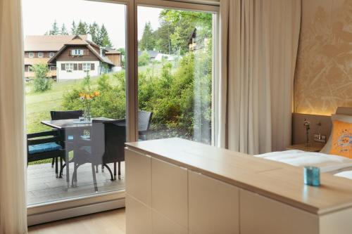 Habitación con ventana grande y mesa de comedor. en Strandhotel am Weissensee, en Weissensee