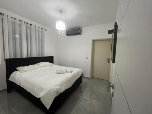 1 dormitorio con 1 cama con sábanas blancas y TV en סאן בוטיק אילת, en Eilat