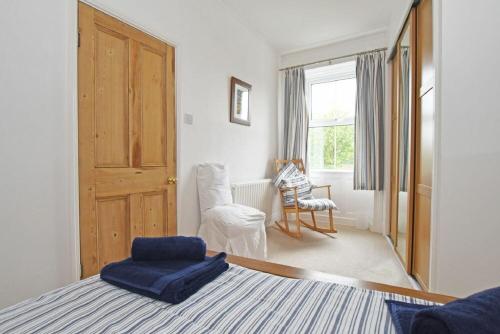 1 dormitorio con 1 cama, 1 silla y 1 puerta en Riverside Cottage en Warkworth