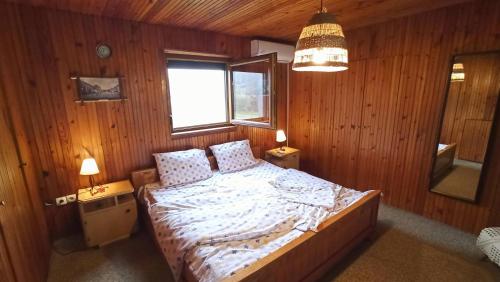 Un dormitorio con una cama con paredes de madera y una ventana en Takovski konak en Gornji Milanovac