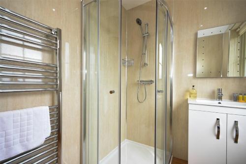 a bathroom with a shower with a glass door at Castle View Glororum in Bamburgh