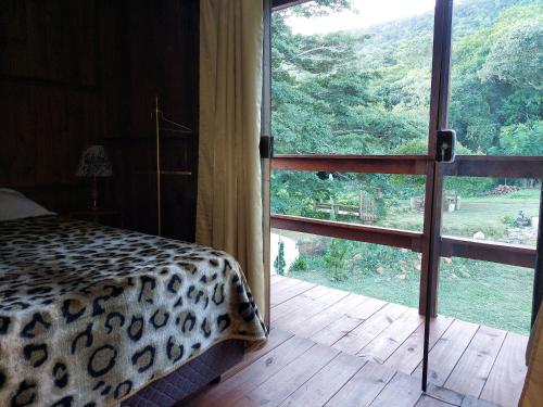 a bedroom with a leopard print bed and a large window at Recanto da Paz - Aos pés do Morro da Borússia in Osório