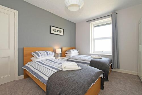a bedroom with two beds and a window at Cladach Cottage in Seahouses