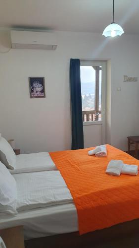 a bedroom with a bed with an orange blanket and a window at Guest House Gurkov in Veliko Tŭrnovo
