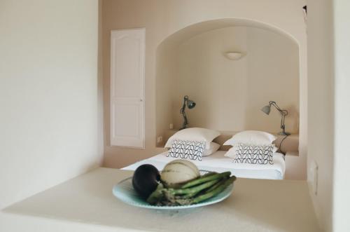 Cette chambre comprend un lit avec un bol de légumes sur une table. dans l'établissement Mas la Buissonniere, à Aigaliers