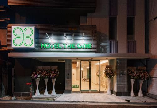 a hotel entrance with a neon sign in front of it at Hotel The One Shinimamiya in Osaka