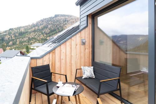 a balcony with two chairs and a table at Alpenhotel & Aparthotel Lanz in Hohentauern