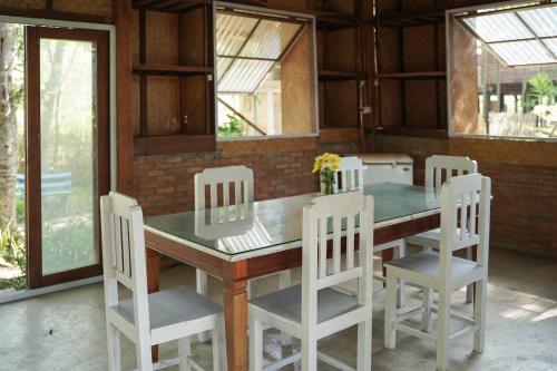 stół jadalny z 4 białymi krzesłami i stołem w obiekcie Art House at Chiangdao - Waterlily House w mieście Chiang Dao