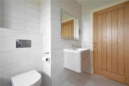 a white bathroom with a toilet and a sink at Rock Lodge in Alnmouth