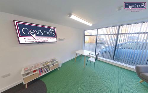 a room with a large window and a desk and a table at Signature House - Contemporary Studios in Coventry City Centre, free parking, by COVSTAYS in Coventry