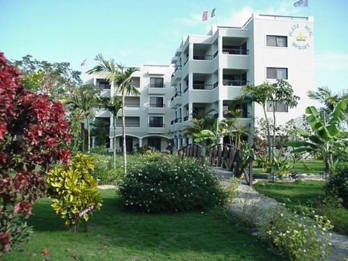 a large white apartment building with trees and bushes at Plaza Real Resort in Juan Dolio